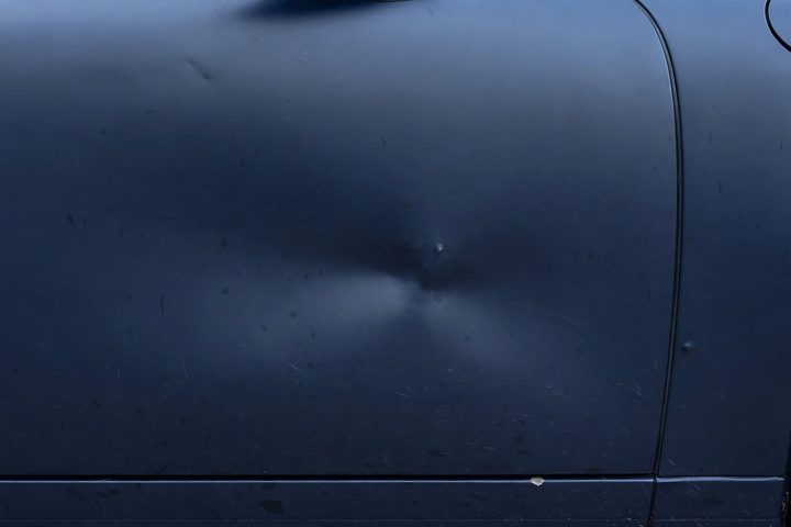 Avant : bosse ronde marquée et micro-rayures sur portière bleu nuit