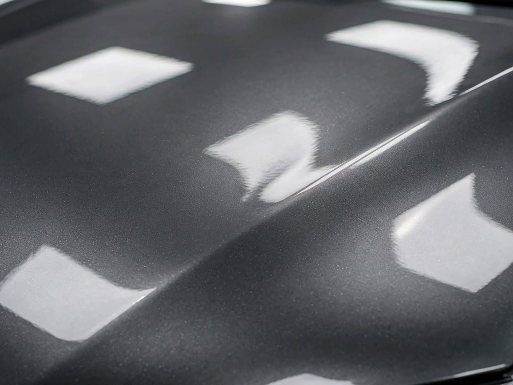 Capot de voiture grise parfaitement remis en forme après débosselage sans peinture : reflets réguliers, teinte d'origine intacte