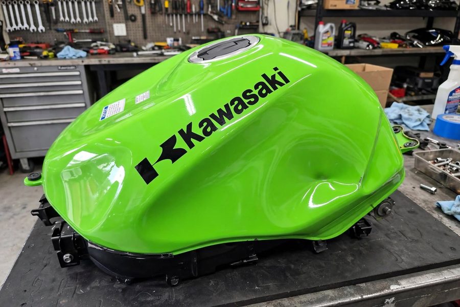 Bosse sur un réservoir de Kawasaki verte avant débosselage sans peinture