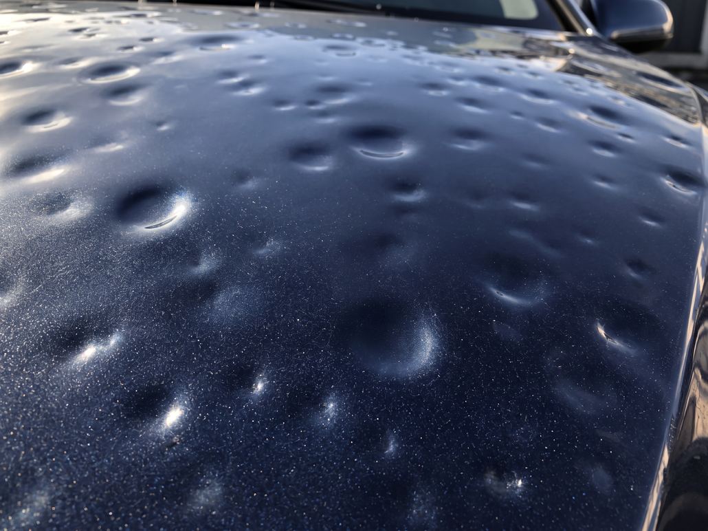Capot de SUV bleu métallisé couvert d'impacts de grêle, peinture d'origine intacte : les dégâts à photographier en lumière rasante dès l'étape 1