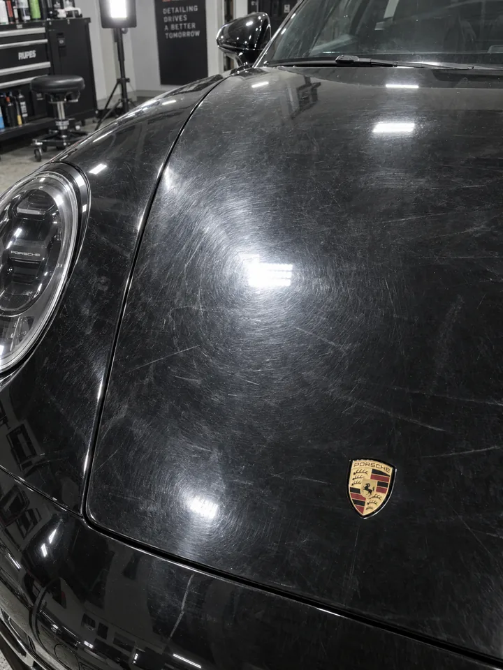 Avant polissage : capot de Porsche 911 noire voilé, hologrammes et micro-rayures dans le vernis