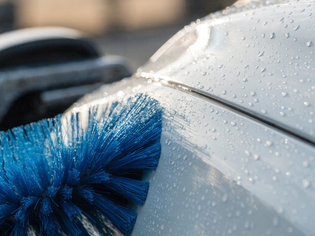 Brosses textiles bleues d'un portail de lavage automatique au contact d'une carrosserie